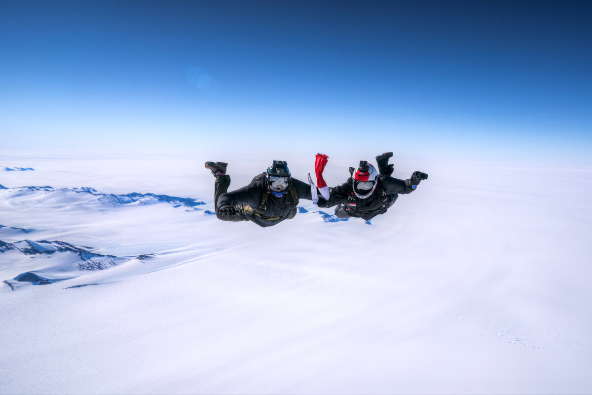 Skydivers prepare to display a flag during free fall